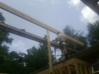 Carpenter setting a ridge beam over a new addition frame — Ice Dam Removal by Roofing Brothers in Oliver Springs