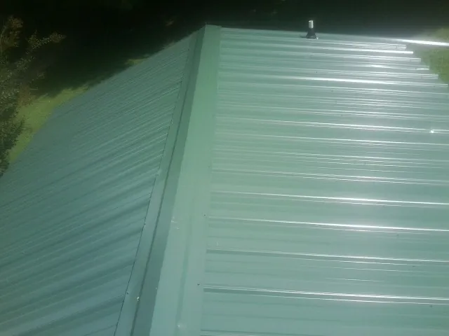 New green metal panels meeting at the ridge of a roof — Flat Roof Repair work by our crew in Oliver Springs