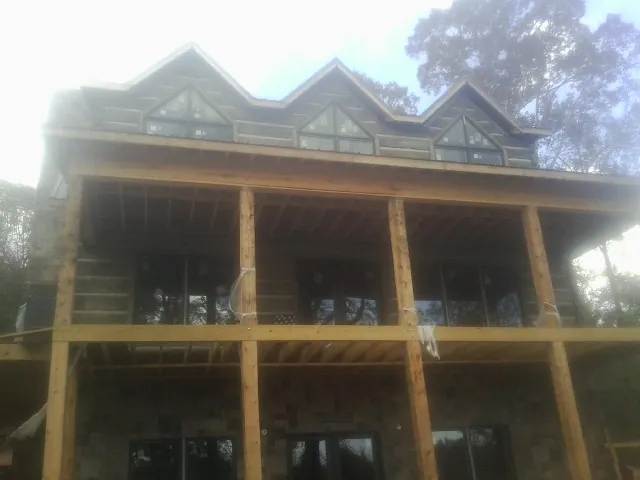 Dormers and porch framing on a large log home under construction — Roof Coating work by our crew in Oliver Springs