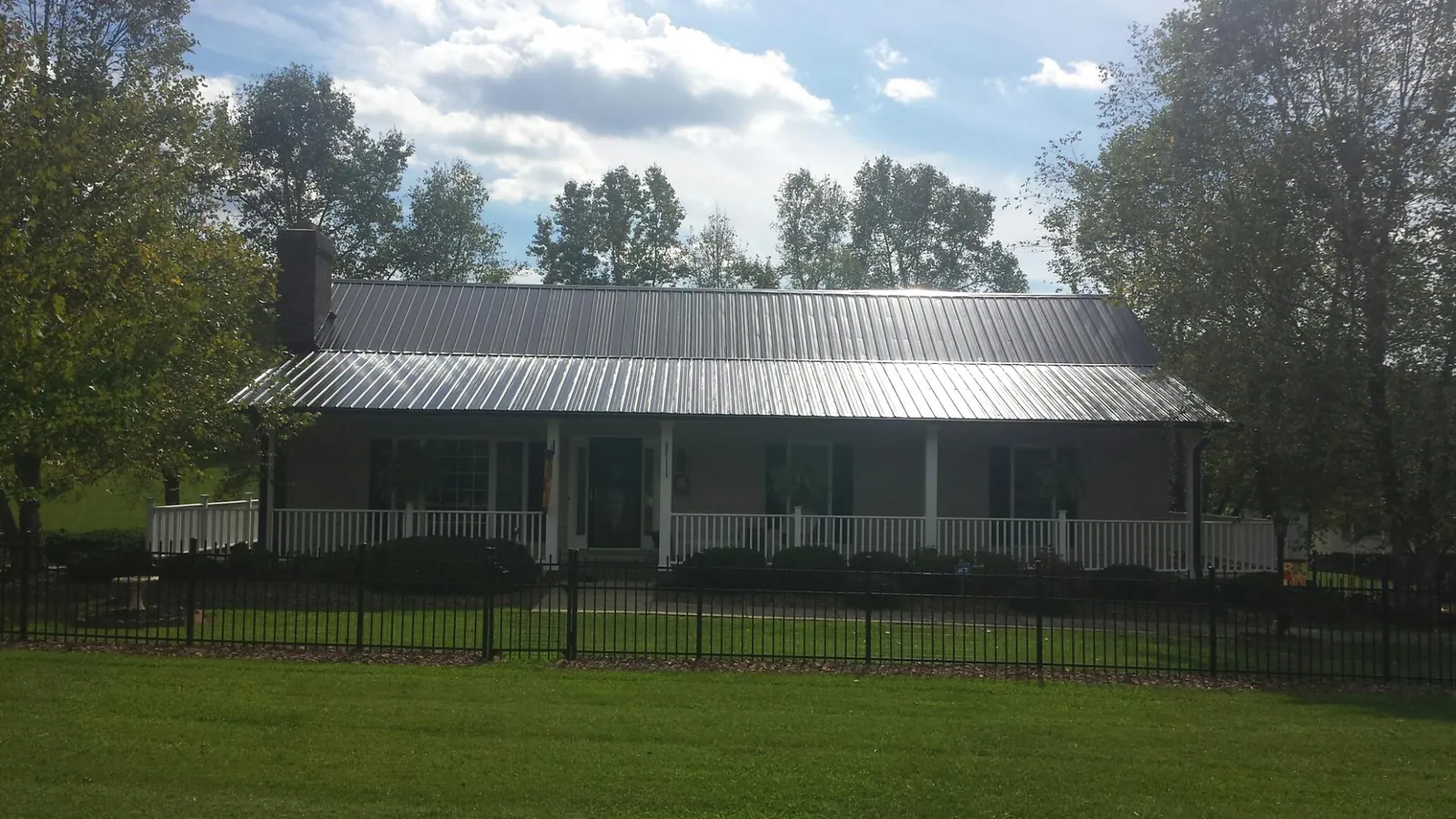 Gray metal roof on a brick ranch with a full width front porch — Gutter Guard Installation work by our crew in Oliver Springs