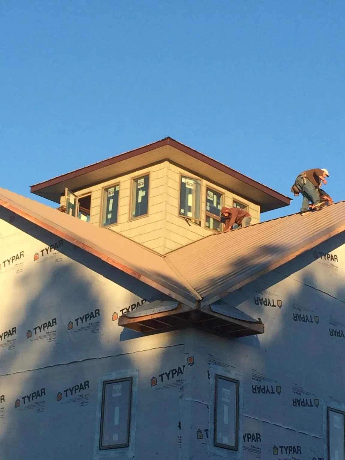 Roofers working around a rooftop cupola on a new metal roof at sunset — Roof Waterproofing in Oliver Springs by Roofing Brothers